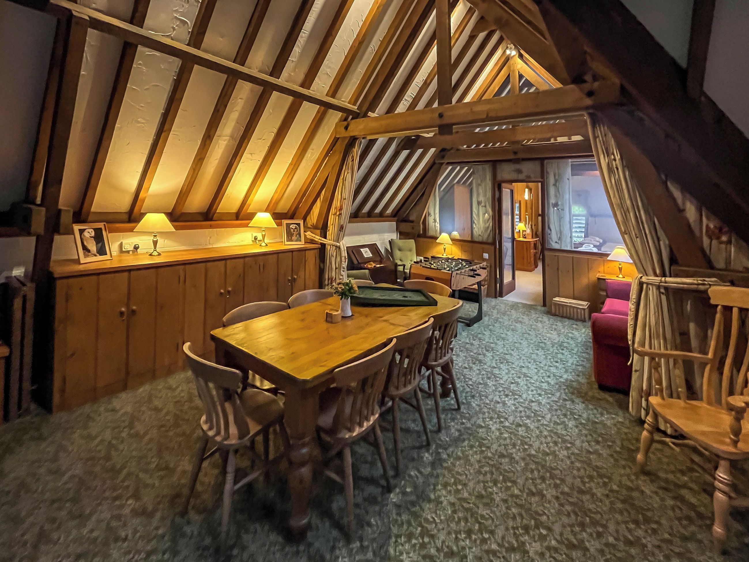 A cozy, wooden-furnished dining area with a high ceiling and a sloped roof.