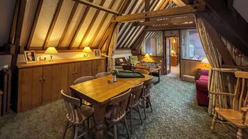 A cozy, wooden-furnished dining area with a high ceiling and a sloped roof.