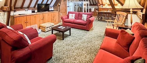 A cozy living room with red sofas, a coffee table, and a wooden ceiling.