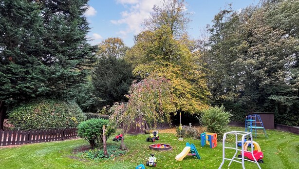 Ein gepflegter Garten mit Schaukel, Spielgeräten und Rasen.