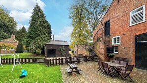 Ein Backsteinhaus mit einer Holzterrasse, einem Picknicktisch und Gartenmöbeln.