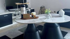 A modern living room with a round table, black ottomans, a TV, and a small Buddha statue. - Revival Ofdreams Mourão (Mourão)