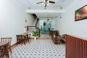A spacious living area with a patterned floor, a staircase, and a dining area with wooden furniture.