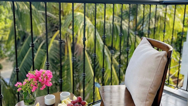 A balcony with a table set for breakfast, including a plate of fruit, a vase of flowers, and a cup. - Peaceful House located at central, 3 minutes walk to The old town & night market (Thành phố Hội An)