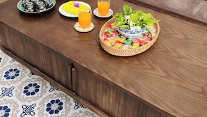 A wooden coffee table with a decorative plate, teapot, and glass of orange juice. - Peaceful House located at central, 3 minutes walk to The old town & night market (Thành phố Hội An)