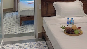 A hotel room with a bed, a window with curtains, a painting of boats, and a fruit basket on the bed. - Peaceful House located at central, 3 minutes walk to The old town & night market (Thành phố Hội An)