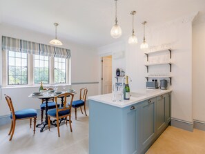 A kitchen with a blue island, white cabinets, and hanging pendant lights. - Eagles Nest at Greyfriars - UK33356 (Winchelsea)