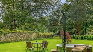A garden with a stone wall, a hot tub, and outdoor furniture. - Heron's Wood at Greyfriars - UK33357 (Winchelsea)