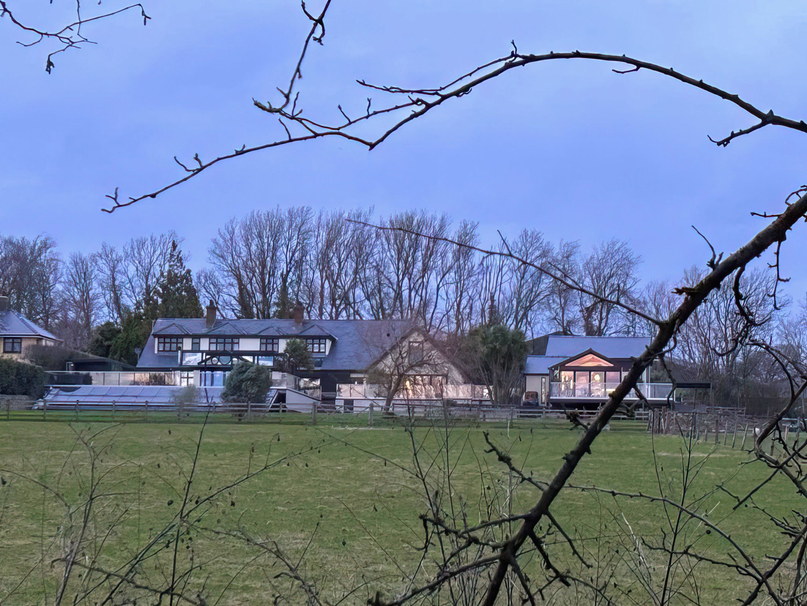 A residential area with multiple houses, a fenced yard, and leafless trees.
