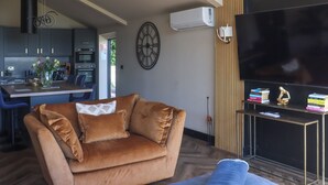 Un salon avec un canapé, un téléviseur et un coin repas, avec une cuisine en arrière-plan.