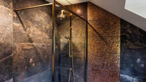 Een moderne douche met glazen cabine, een handdouche en een wandmengkraan.