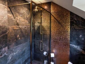 Eine moderne Dusche mit Glasabtrennung, Handbrause und Wandarmatur.
