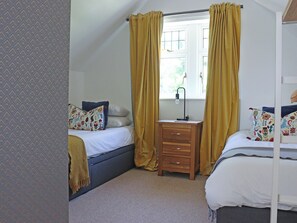 A bedroom with two beds, a bedside table, a window with curtains, and a patterned wall. - Deerview Lodge - UK51044 (Bonvilston)