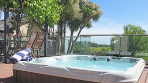 A hot tub on a wooden deck with chairs and a glass railing. - Deerview Lodge - UK51044 (Bonvilston)