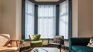 A cozy living room with a wooden coffee table, a green armchair, a black armchair, and a teal sofa.