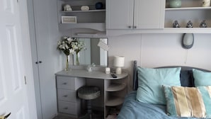 A bedroom with a bed, a desk, and a wardrobe.
