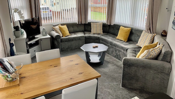A compact living space with a sofa set, a small dining table, and a TV.