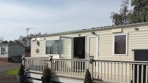 A mobile home with a front porch, a sliding door, and a small deck area.