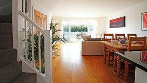 Amplia sala de estar con una mesa de comedor de madera, un sofá y una escalera que conduce a otro nivel.