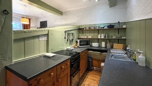 A compact kitchen with green cabinets, a black countertop, a microwave, and a sink. - Saddle Room - UK51017 (Louth)
