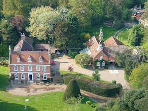 Une grande maison traditionnelle en briques, dotée de nombreuses cheminées et d’un jardin bien entretenu.