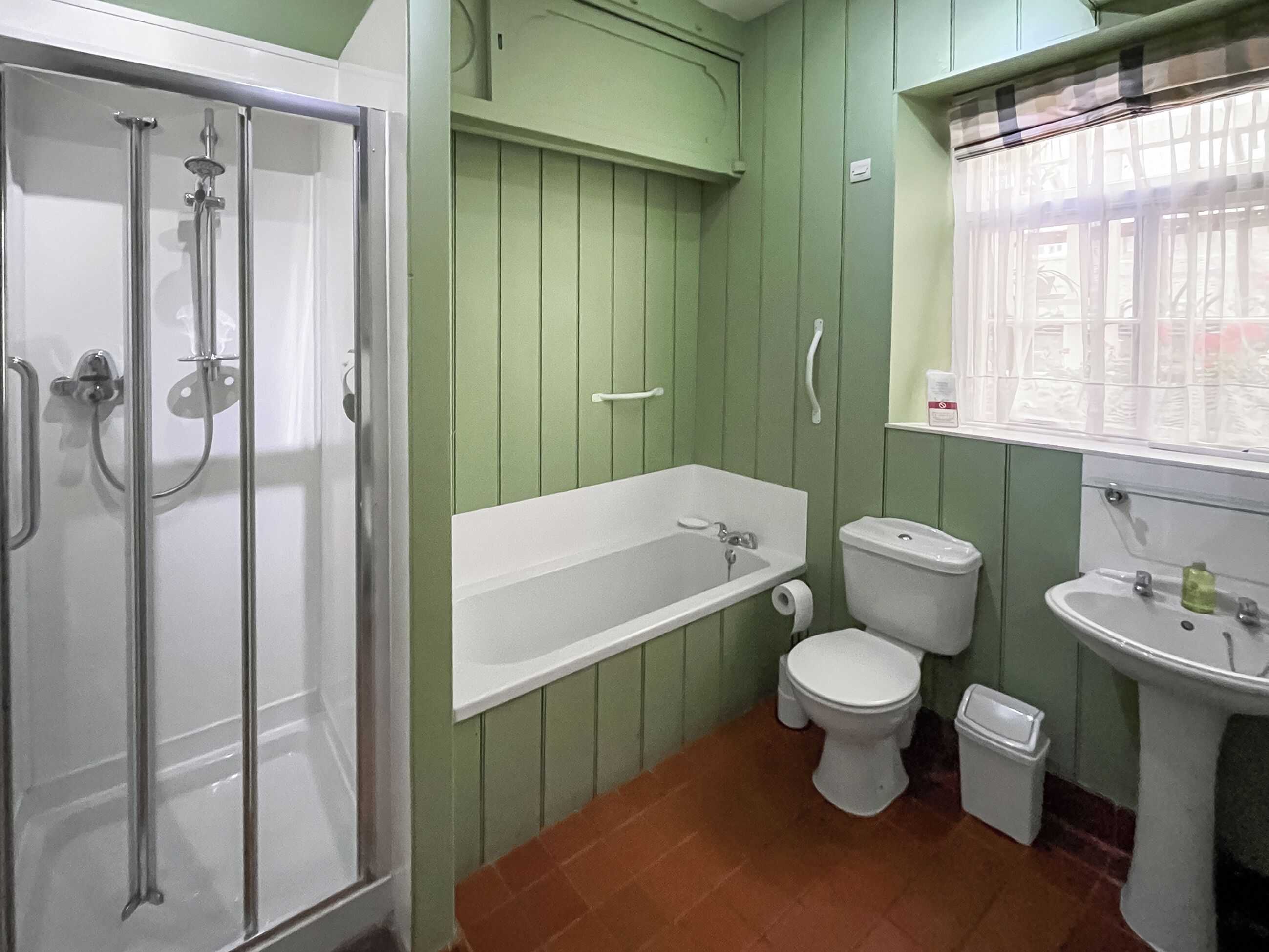 Ein Badezimmer mit einer einteiligen Duschkabine, einer weißen Badewanne, einer weißen Toilette und einem Standwaschbecken.
