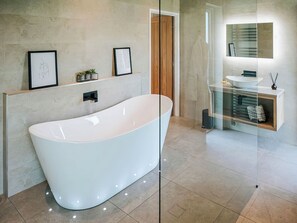 A modern bathroom with a freestanding bathtub, a glass-enclosed vanity, and a wooden door. - 1 bedroom accommodation in Clitheroe (Clitheroe)