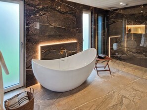 A modern bathroom with a freestanding bathtub, marble walls, and a minimalist design. - 1 bedroom accommodation in Clitheroe (Clitheroe)