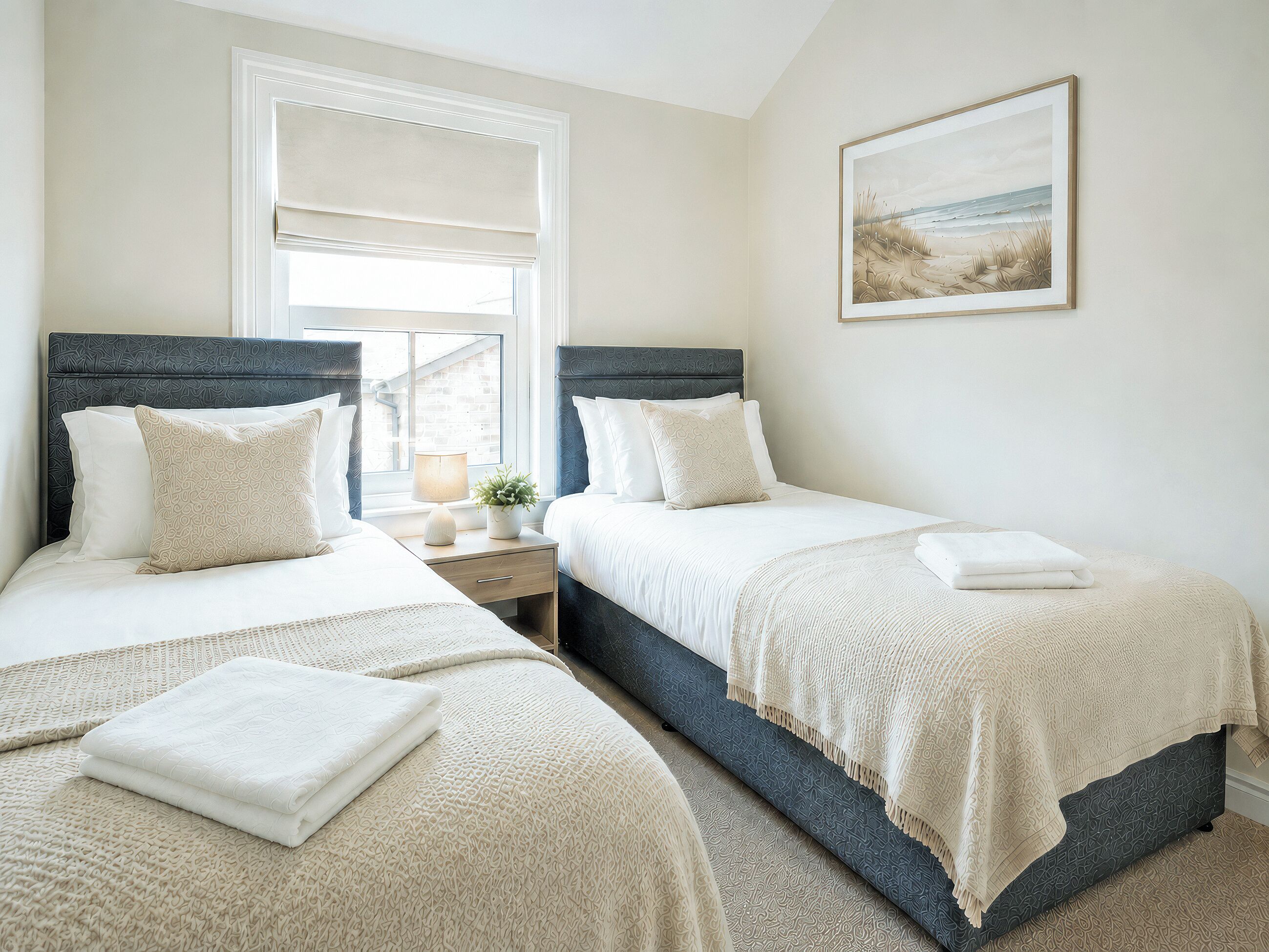 Quarto com duas camas, janela com persianas, mesa de cabeceira com abajur e planta, e um quadro na parede.