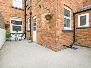 A brick building with a patio area, outdoor seating, and hanging flower baskets. - The Townhouse - UK37120 (Scarborough)