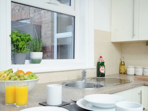 A kitchen with a window, a sink, a bowl of fruit, and a bottle of Fairy dishwashing liquid. - The Townhouse - UK37120 (Scarborough)