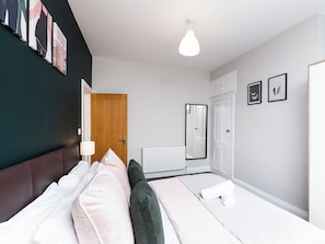 A modern bedroom with a bed, a wooden door, a radiator, and a white wardrobe. - Ashville Lodge - UK37119 (Scarborough)
