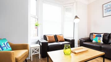 A modern living room with a brown leather sofa, a wooden coffee table, and a small white side table.