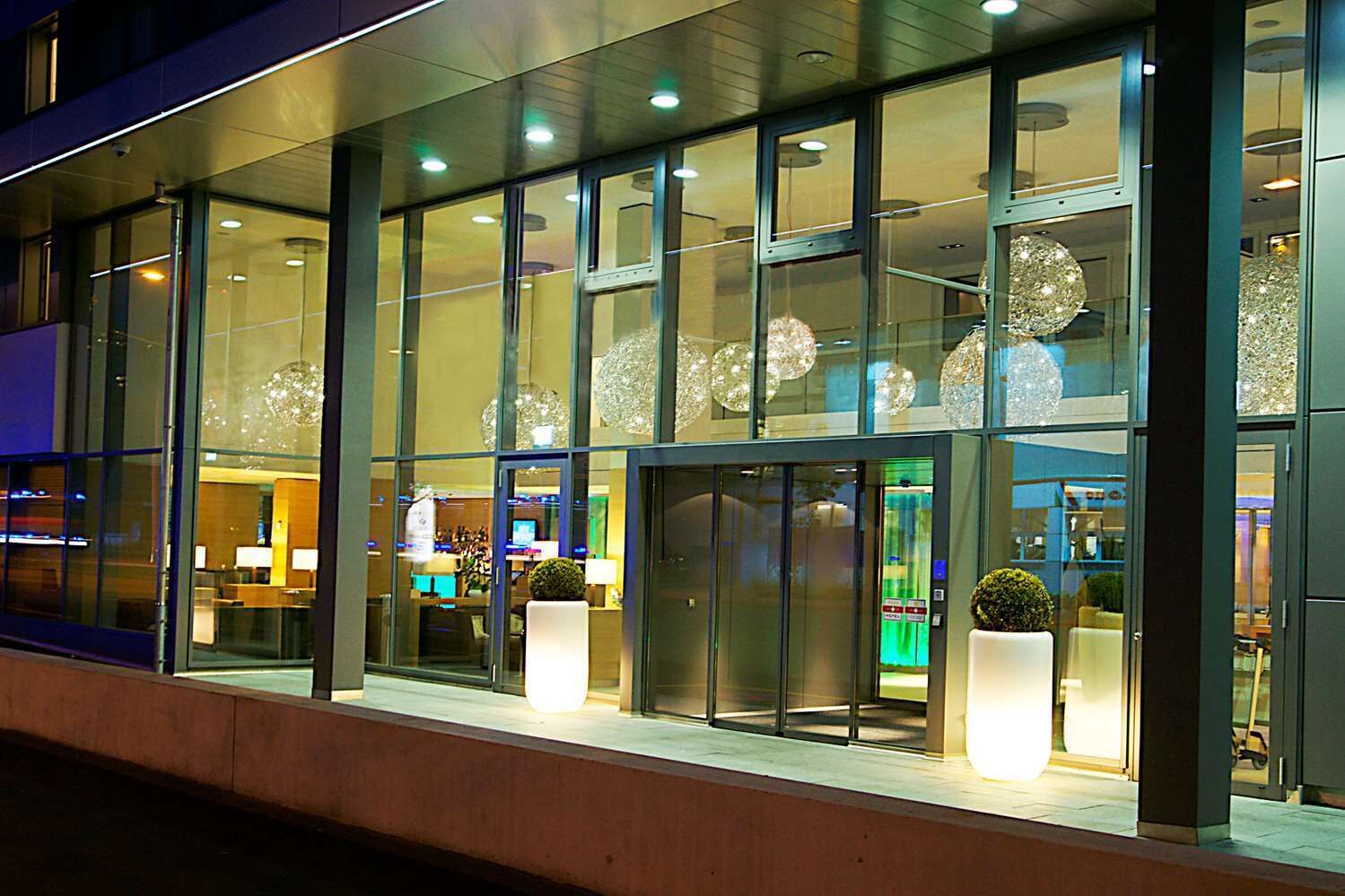 A modern building with large glass windows, a reception area, and decorative spherical lights.