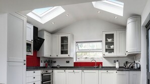 A modern kitchen with white cabinetry, a black countertop, a skylight, and a window. - 3 bedroom accommodation in Beaumaris (Beaumaris)