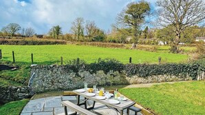 A stone patio with a picnic table set for four, surrounded by a stone wall and a grassy field. - 3 bedroom accommodation in Beaumaris (Beaumaris)