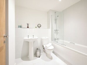Une salle de bain moderne équipée d’un lavabo, de toilettes et d’une douche à parois de verre.