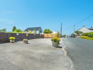 A residential street with houses, a wooden fence, and flower pots.