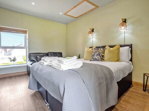 A bedroom with a bed, a window, and two wall-mounted lights.