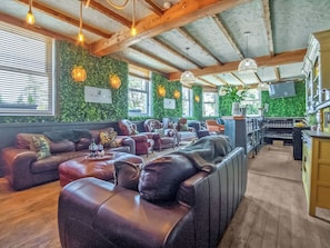 Ett mysigt loungeområde med lädersoffor, en bar och gröna väggar.