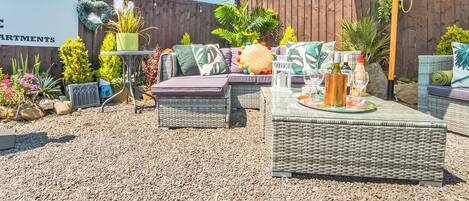 A patio area with outdoor furniture, a table with drinks, and a wooden fence.