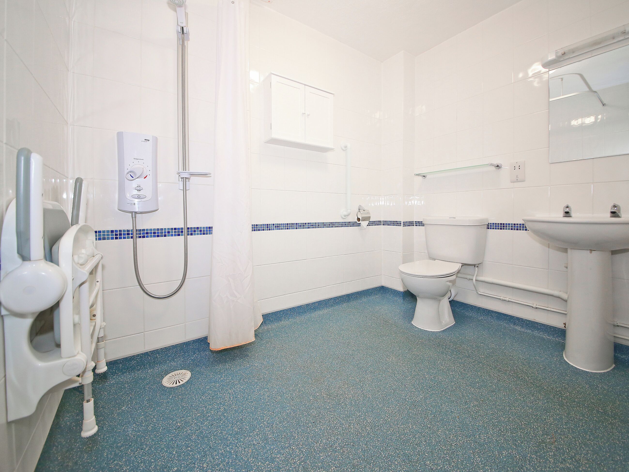 Une salle de bain équipée de toilettes, d’un lavabo, d’une douche et d’un sèche-mains.