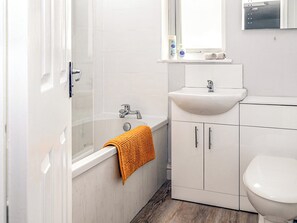 Een moderne badkamer met een badkuip, een wastafel en een toilet.