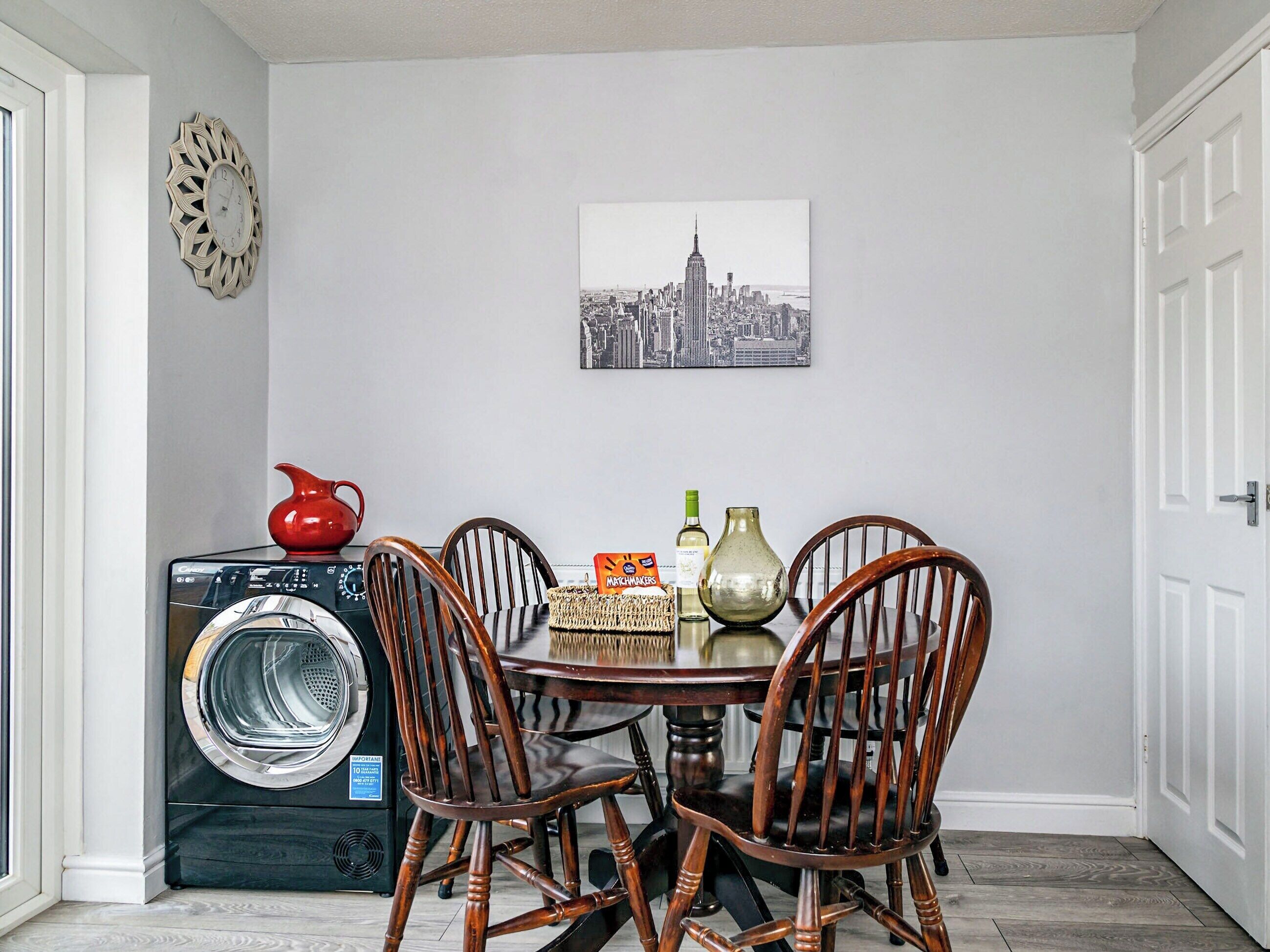 Un espacio habitable compacto con zona de comedor, lavadora y una obra de arte urbana en la pared.