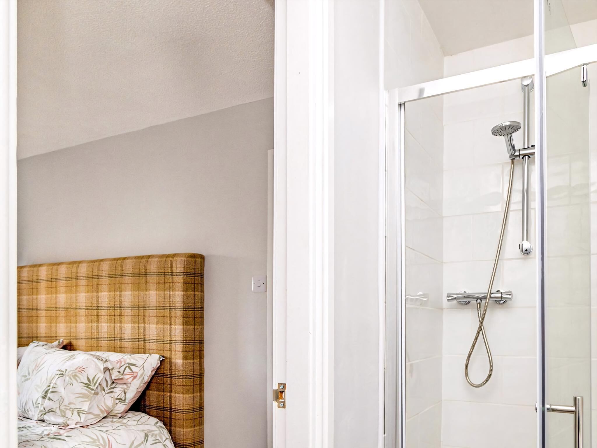 Una habitación con una cama, ducha y puerta.