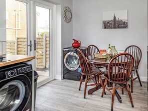 Una cocina funcional con lavadora, una mesa de comedor con sillas y un cuadro con vista a la ciudad.