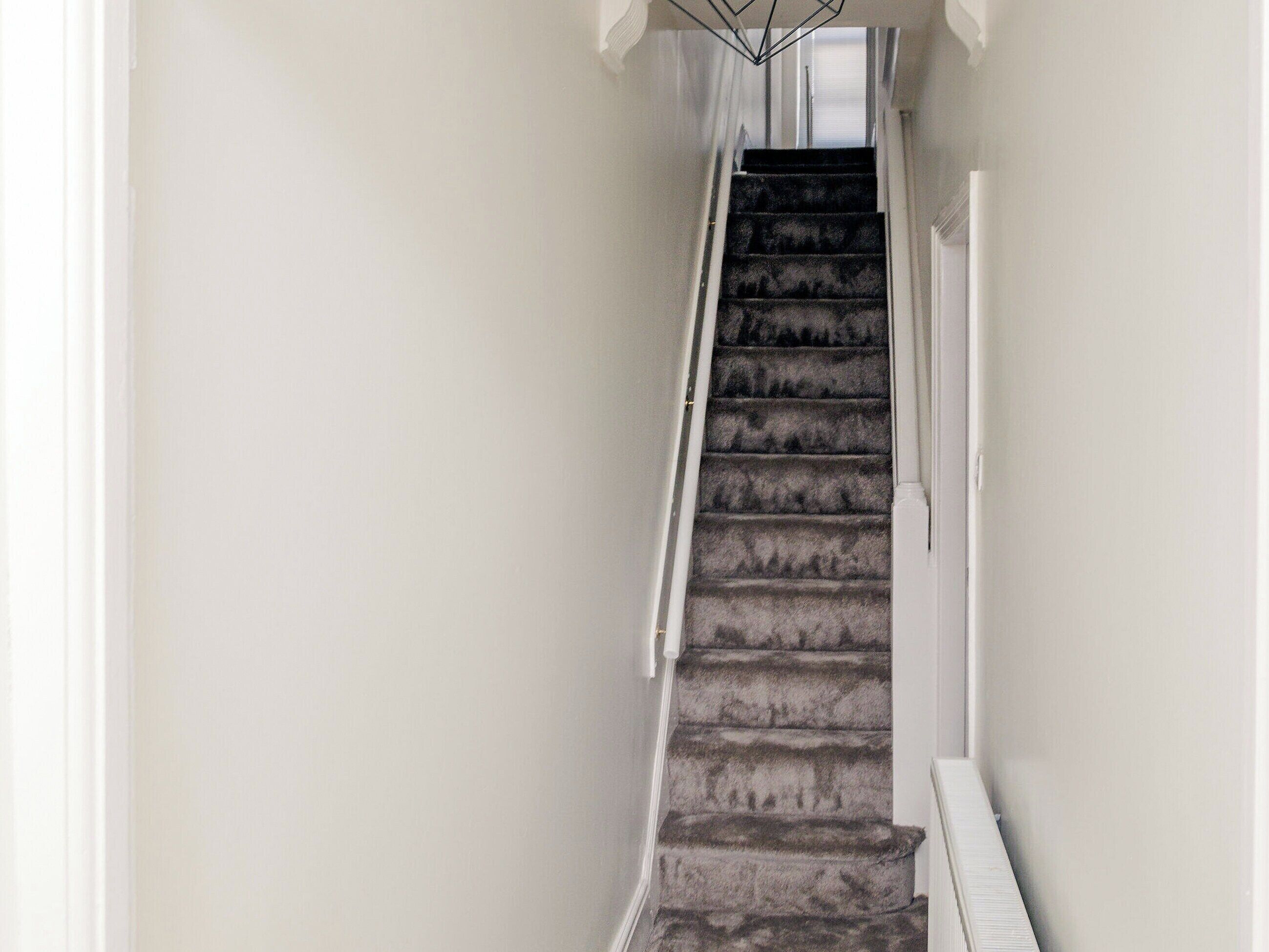 A staircase with carpeted steps leading to a landing.