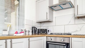 Een moderne keuken met witte kasten, een inbouwoven en een gasfornuis.