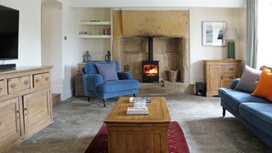 A living room with a stone fireplace, a television, sofas, and a coffee table.