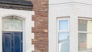 A corner building with a dark blue door, white brick walls, and a window with blinds. - Newport House Crindau Road Upper (Newport)
